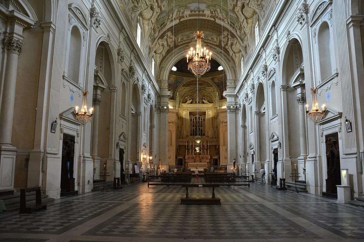 Det lange hvide skib i Santa Maria del Carmine i Firenze, med høje pilastre, hængende lysekroner, et ternet stengulv og højalteret for enden